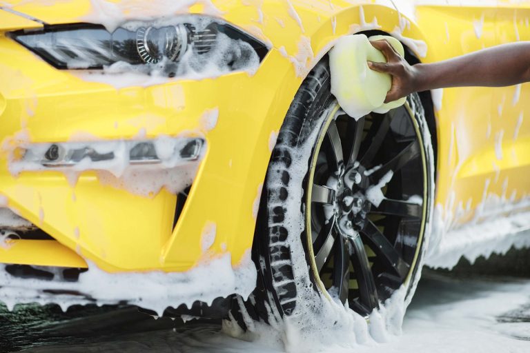 Cleaning of modern rims of luxury yellow car at self car wash service outdoors