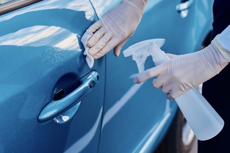 Woman disinfects a car door handle with an antibacterial spray